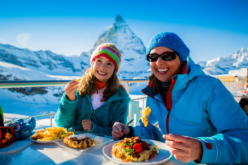 family eating lunch in front of the matterhorn after skiing