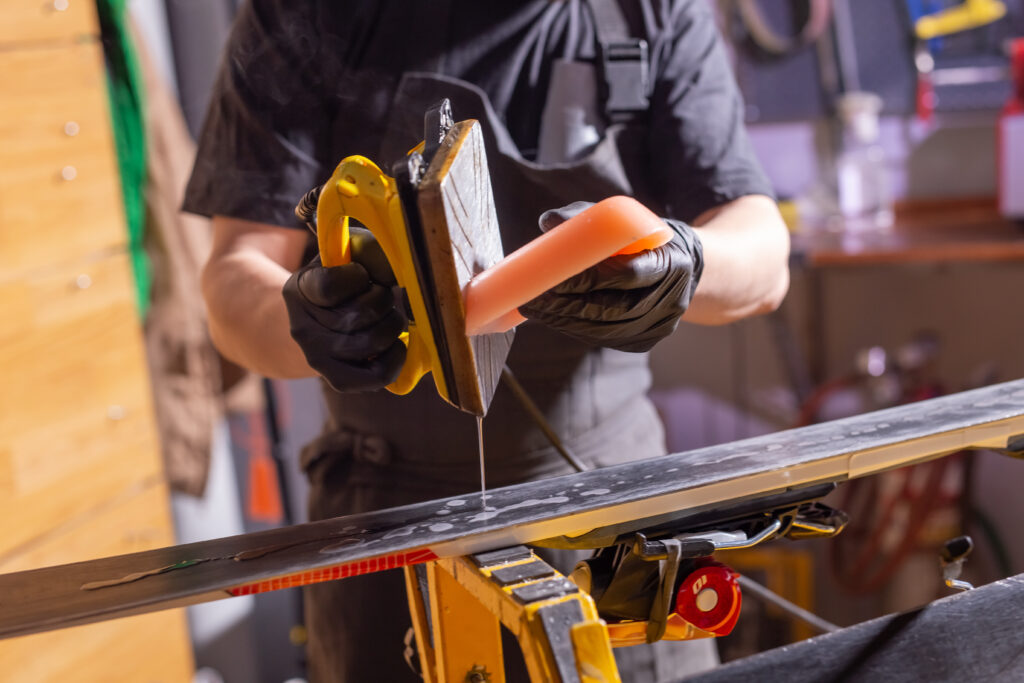 ski repair technician waxing skis