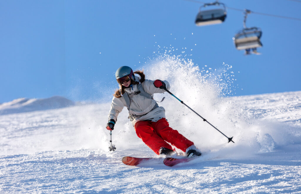 girl skiier in a white jacket and red pants