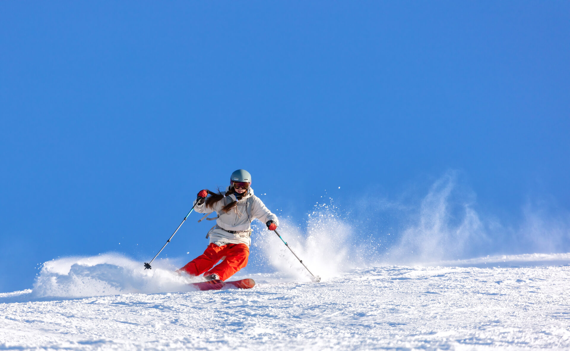 Girl skier in a white jacket and red pants