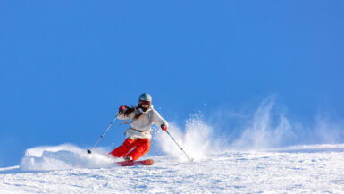 Girl skier in a white jacket and red pants