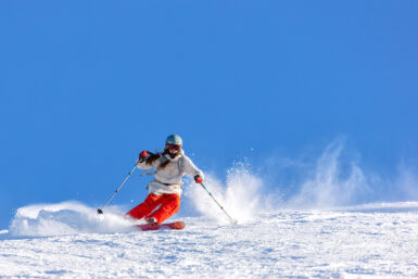 Girl skier in a white jacket and red pants